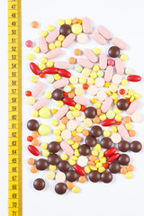 Colorful medical pills and centimeter on white background, health care, healthy lifestyle and slimming concept