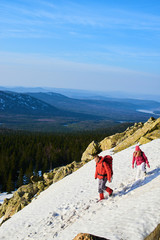 A group of tourists consisting of a guy and girl goes on a snowy mountain slope