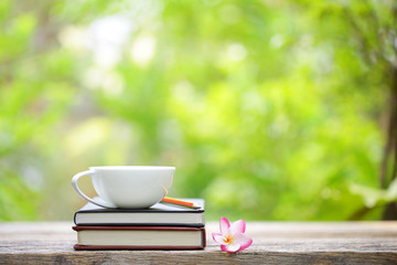 Notebook with flower and cup on wooden table