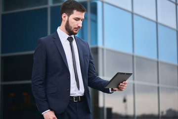 Businessman holding tablet on background of buildings with glass facades