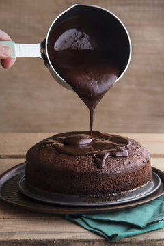 Close up of melted dark chocolate pouring over a cake