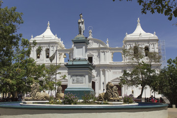 Monumento de máximo jerez y la catedral en la parte trasera acompañada de arboles y el cielo azul