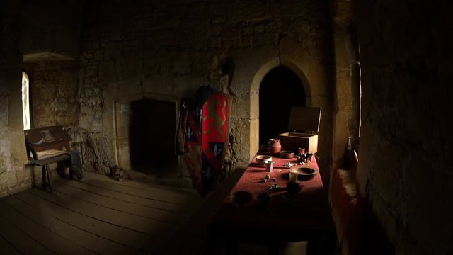 View of a dark medieval room in a castle with light coming from two small windows