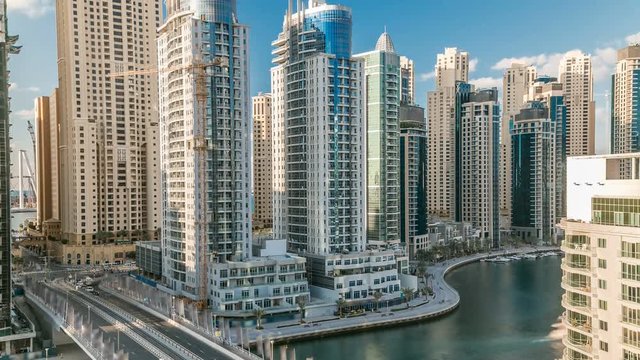 Dubai Marina at evening timelapse with trails of boats on the water and cars traffic, Dubai, UAE