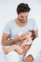 Obraz na płótnie Canvas Father feeding milk to daughter at home