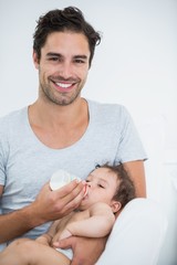 Man feeding milk to baby girl