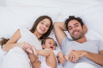 High angle view of couple lying on bed with baby