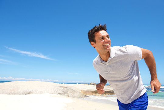 Cheerful middle aged man running on the beach