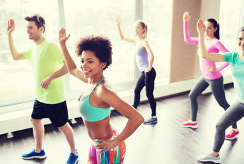 group of smiling people dancing in gym or studio