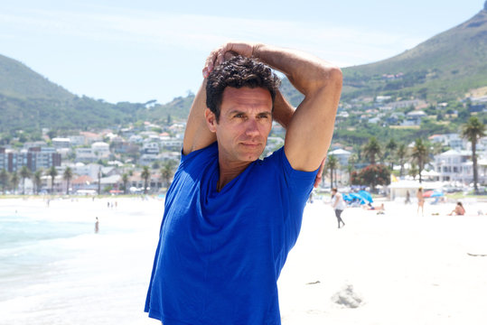 Older Active Man Stretching Exercise At The Beach