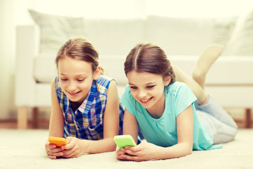 Obraz na płótnie Canvas happy girls with smartphones lying on floor