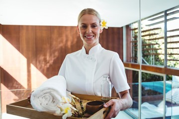 Smiling masseuse holding a tray at the spa