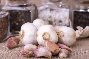 fresh garlic surrounded by containers with herbs