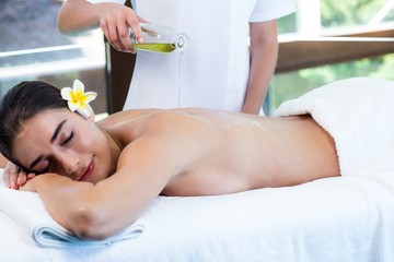 Masseuse pouring massage oil on woman