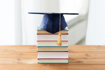 close up of books and mortarboard on wooden table