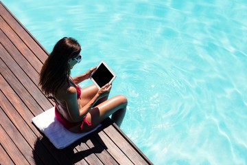 Woman using her tablet on pool edge