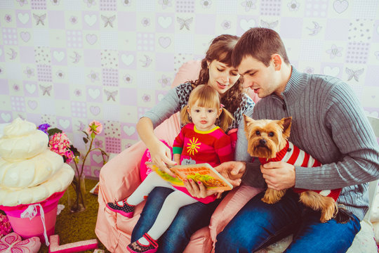 Young family is reading a book with a daughter