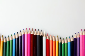 many colored pencils are in the shape of a wave near each other on a white isolated background