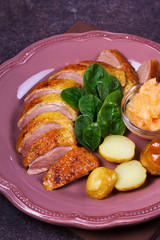 Spiced slow roast duck, apple sauce, spinach and potato, served on pink plate