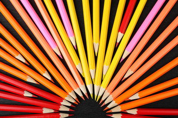 Fototapeta premium a lot of colored pencils closeup on wooden background lined circle