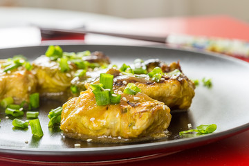 Chinese Stuffed Cabbage (Rolls) with Meat and Onion on the Black Plate on the Red Background, Close-up