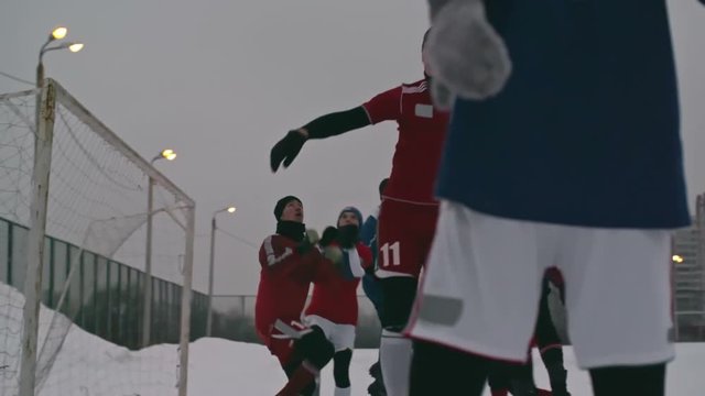 Teenage soccer goalkeeper making a save after goal attack during a match at outdoor stadium in winter