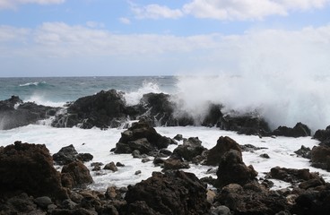 Wild sea with breaking waves on black lava rocks on the east coast of Lanzarote, Canary Islands, Spain. In the Northeast of the Island between Arrieta and Orzola.. 