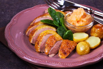 Spiced slow roast duck, apple sauce, spinach and potato, served on pink plate