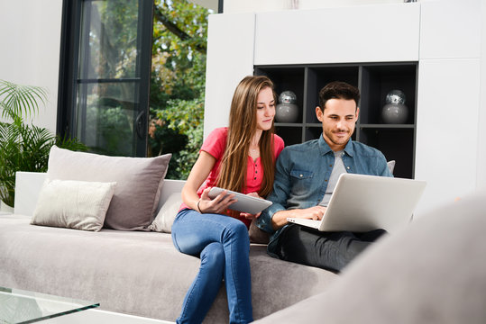 cheerful young couple man and woman in sofa at home with laptop computer