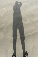 a shadow cast on the beach facing the ocean