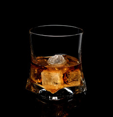 Whiskey with ice in glass isolated on black background 