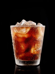 Cold cola with ice in a glass on a black background

