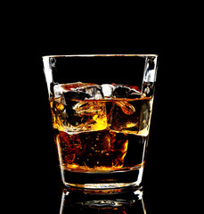 Whiskey with ice in glass isolated on black background 