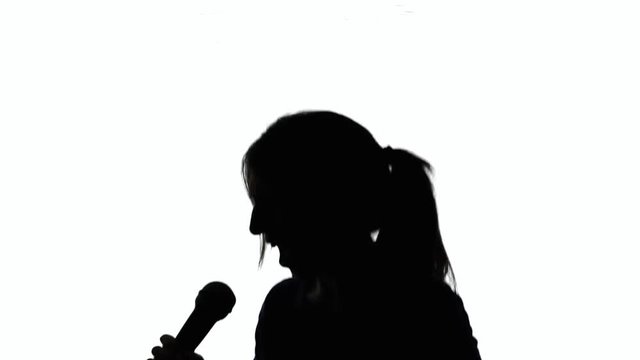 A crazy singer (a woman) moving, shaking, singing into a microphone. Silhouette shot.