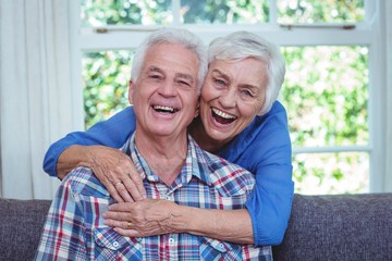 Senior woman laughing while embracing husband from behind