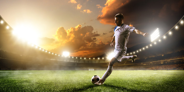 Gracz piłki nożnej w akci na zmierzchu stadium panoramy tle