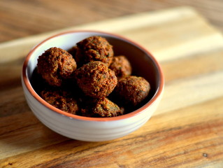 Falafel; Deep fried falafel balls in a bowl on a wooden board.