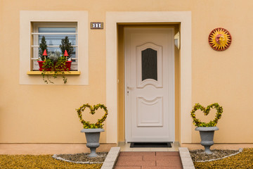 Schöner Eingang eines Einfamilienhauses mit Haustür aus PVC und Dekor mit Sonne und Herzen