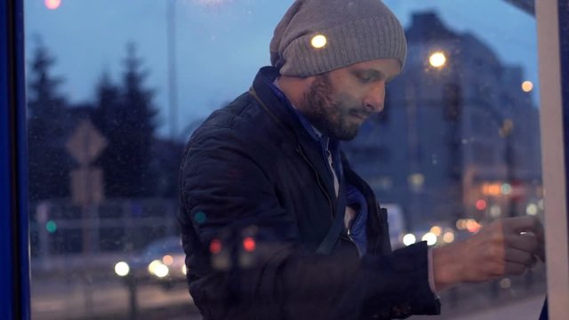 Young man buying ticket from vending machine at tram station
