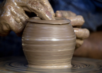 Close-up view of master working on pottery wheel and making clay pot