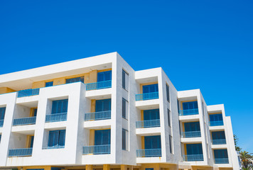 White living house with appartments and balconies in   blue color with sky background