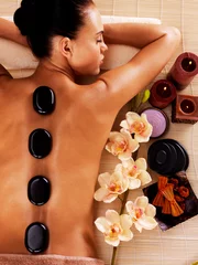 Raamstickers Adult woman relaxing in spa salon with hot stones on body © Valua Vitaly