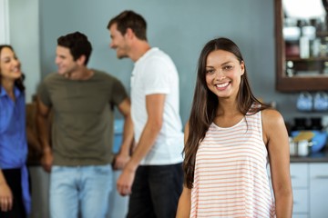 Happy young woman with friends in background at home