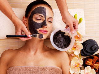 Cosmetologist smears cosmetic mask on the face of  woman