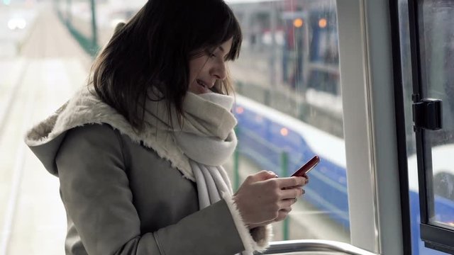 Young, pretty woman using smartphone during tram ride
