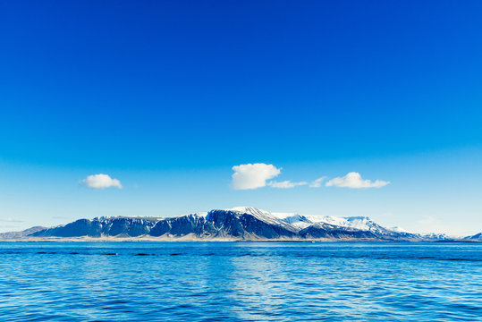 Fototapeta Blue ocean with distant mountains
