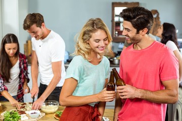 Smiling young couple toasting beer bottles at home
