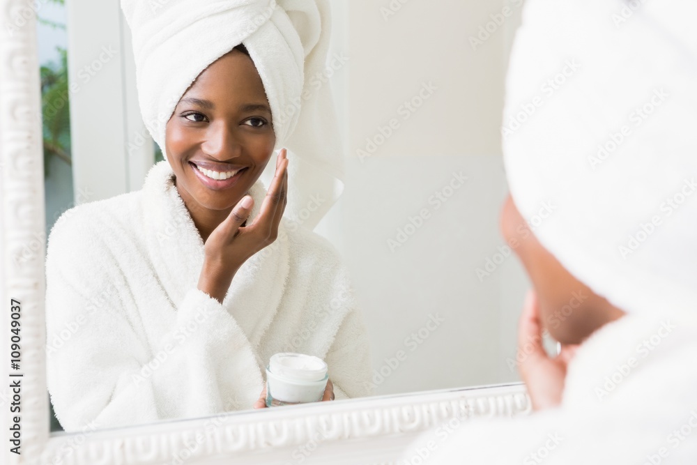 Wall mural young woman applying moisturizer