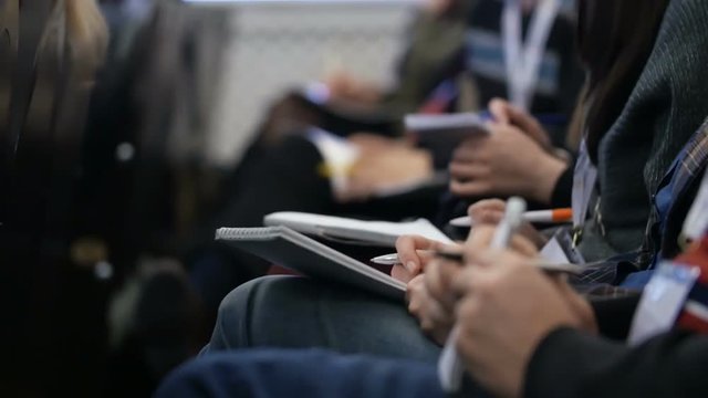Close-up of Hands holding pens and making notes at the conference