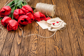 Tulips bouquet and decor with coarse thread on a wooden background.